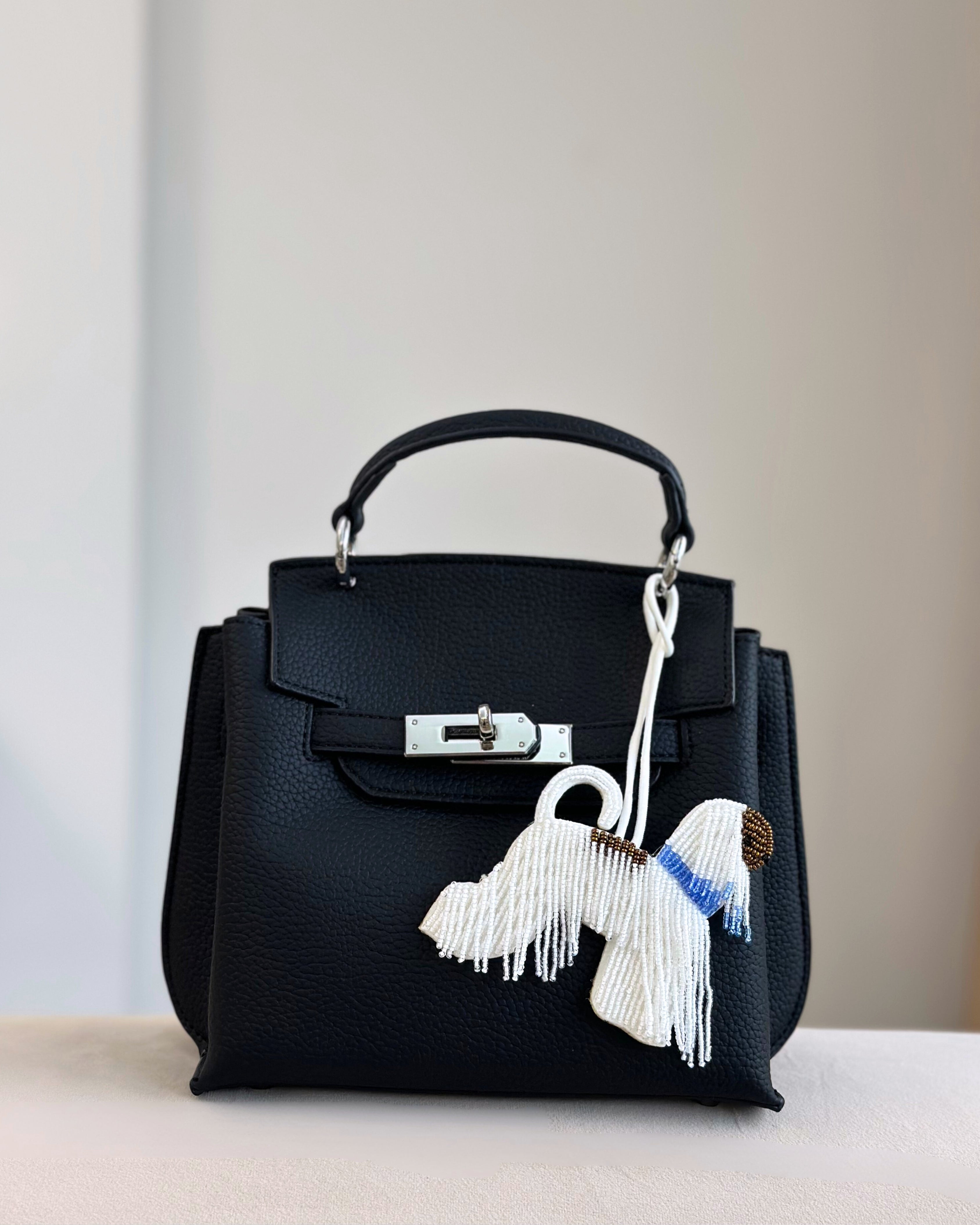Black handbag with tassel details on a neutral background