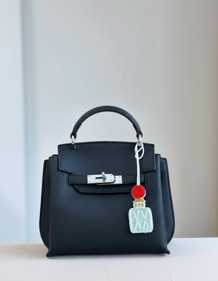 Black handbag with a decorative charm on a light background